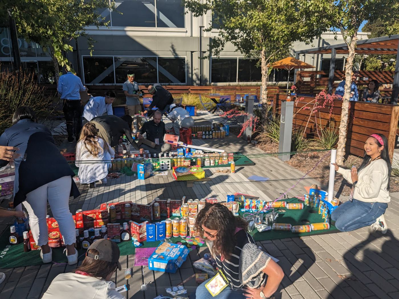 Teammates organize cans along a miniature golf green