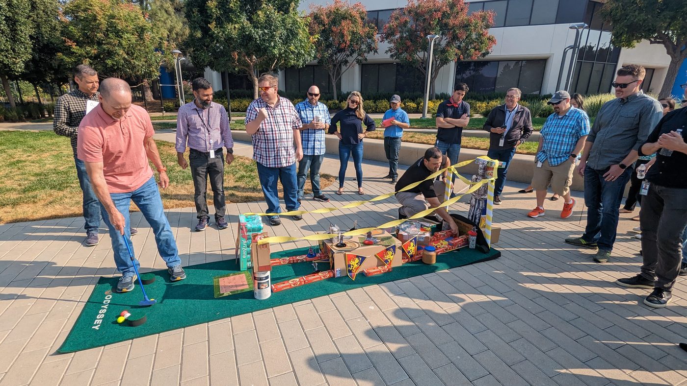 A team watches a putt through the obstacle course they created